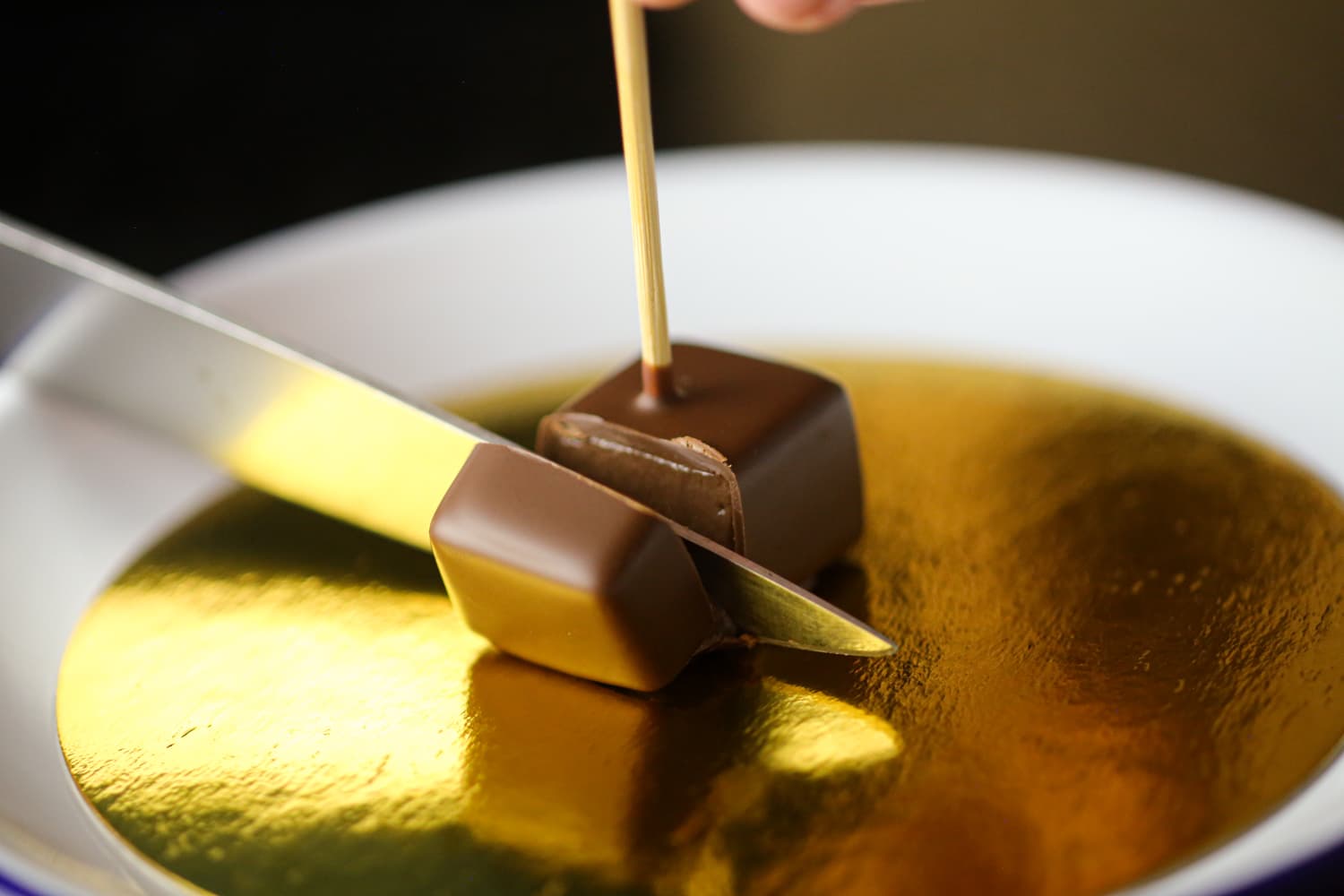 Pot de creme bite being cut by a knife.